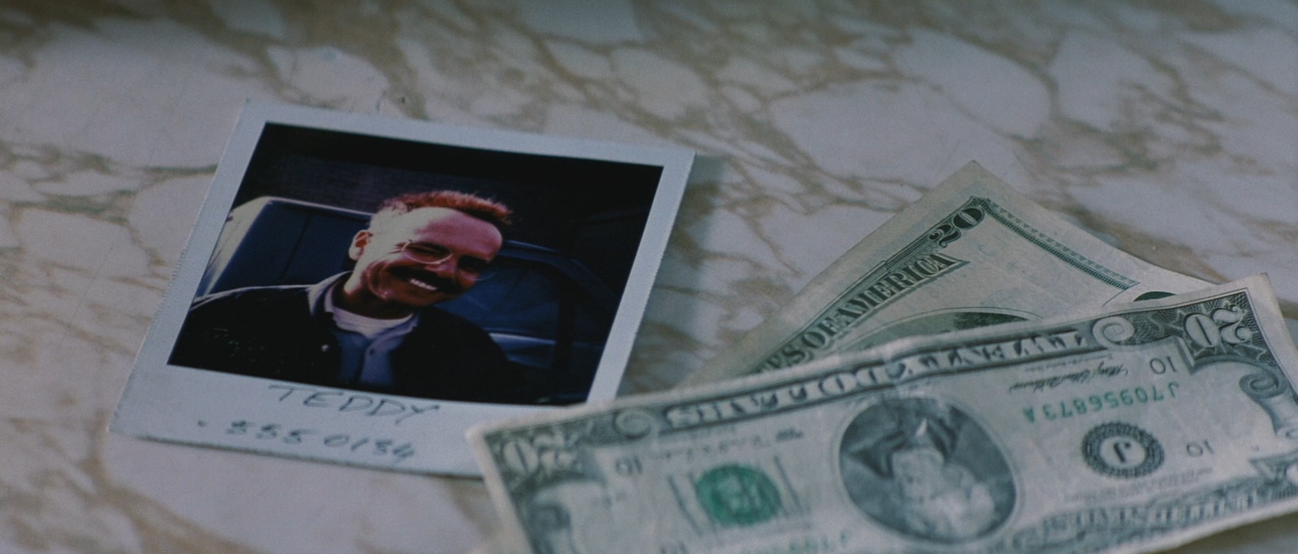 Joe Pantoliano on a Polaroid in a screenshot from Christopher Nolan's *Memento*